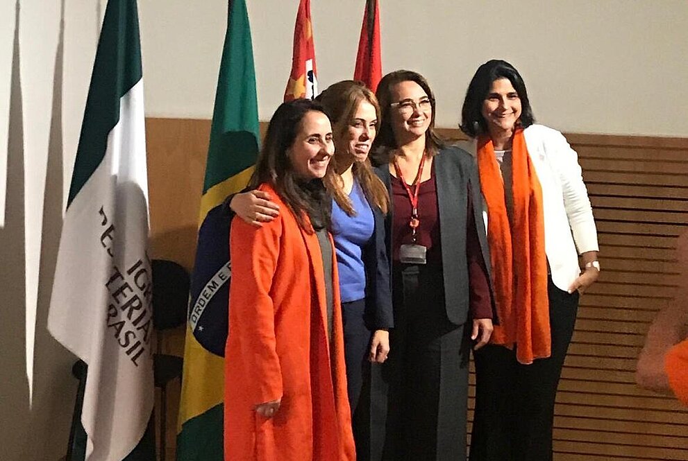 debatedoras posam para foto em frente às bandeiras do Brasil, Mackenzie e outras.