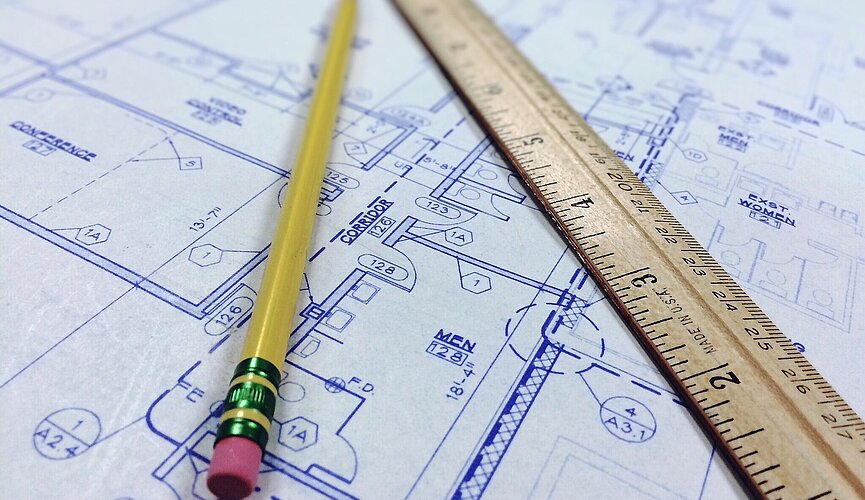Imagem com um projeto de arquitetura desenhado no papel e junto com um lápis e uma régua